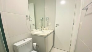 A small, compact bathroom with a toilet, sink, and shower. - In Mare praia de Cotovelo por Carpediem (Parnamirim)