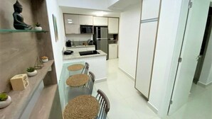 A modern kitchen with a central island, built-in appliances, and a dining area with a table and chairs. - In Mare praia de Cotovelo por Carpediem (Parnamirim)