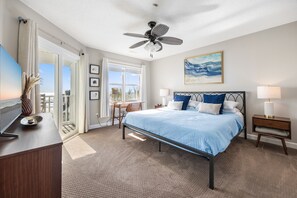 A bedroom with a bed, a desk, a chair, a ceiling fan, a TV, and a window with curtains. - Beachfront House - Dogs OK - Pool, Near Golf (Murrells Inlet)