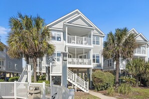 A multi-story beachfront house with a balcony, a staircase leading to the upper floor, and a fenced front yard. - Beachfront House - Dogs OK - Pool, Near Golf (Murrells Inlet)