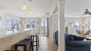 A modern kitchen with a large island, bar stools, and pendant lighting. - "Mermaid's Delight" Oceanfront Beach House w/pool (Murrells Inlet)