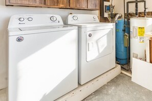 A laundry room with two white front-loading washers and a blue water heater.