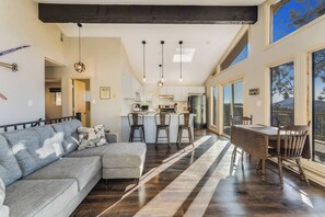 A modern kitchen with a bar area, a dining table with chairs, and a large window offering a view. - Hot tub & Sleep 6 at The Colorado Cabin (Bailey)