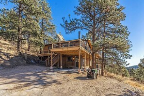 A two-story wooden cabin with a balcony, surrounded by pine trees. - Hot tub & Sleep 6 at The Colorado Cabin (Bailey)