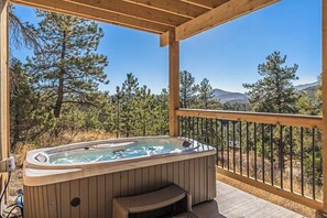Tinaco de hidromasaje en una terraza de madera con vistas a pinos y montañas.