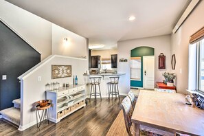 Open-plan living space with a central kitchen island, dining table, and staircase leading to an upper level.