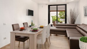 A modern living room with a dining area, a brown sectional sofa, and a large window with a view of greenery. - "Piece of Ocean by Mea Substantia" (Playa de la Américas)