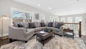 Ein modernes Wohnzimmer mit einem Ecksofa, einem Couchtisch und einem Teppich.