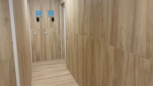 Ein schmaler Korridor mit Holzwänden und Holzboden. Zwei Schilder an der Wand, eines mit der Aufschrift 'TF' und das andere mit 'TE'.