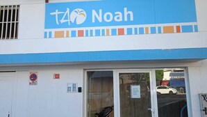 Ein Gebäude mit einer blauen und weißen Fassade, einem Schild mit der Aufschrift "t4 Noah" und einer Tür, in der ein Kinderwagen steht.