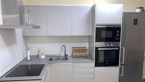 Eine moderne Küche mit weißen Schränken, einer Edelstahl-Spüle, einem eingebauten Ofen und einem Kühlschrank.