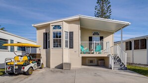 A single-story house with a covered porch, a small staircase, and a golf cart parked outside. - Nettles Island Jensen Beach Home: Walk to Ocean! (Jensen Beach)
