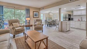 A spacious living room with a dining area, kitchen, and large windows.