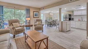A spacious living room with a dining area, kitchen, and large windows.