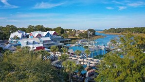 A coastal resort with a marina, beachfront villas, and a boardwalk with umbrellas.