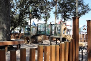 Children can play on the slide and explore the playground area surrounded by a fence.