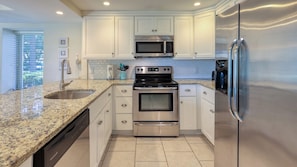 Modern kitchen with stainless steel appliances, white cabinetry, and granite countertops.