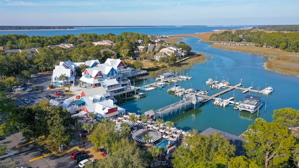 Waterfront property with marina, boats, and lush greenery, offering stunning views of the adjacent beach and ocean.