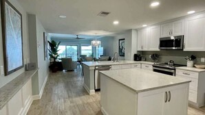 Una cocina moderna con armarios blancos, una isla grande y un microondas integrado.