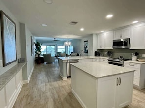 A modern kitchen with white cabinetry, a large island, and a built-in microwave.