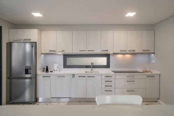 A modern kitchen with a stainless steel refrigerator, a built-in oven, a microwave, and a sink.
