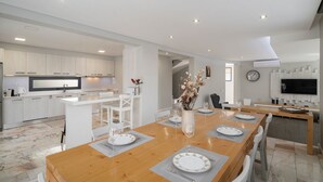 A modern kitchen with white cabinets, a central island, and a dining area with a wooden table set for four.