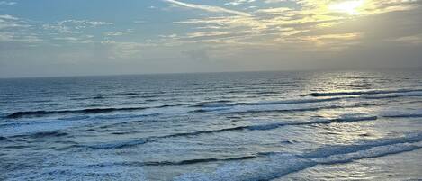 A beach with waves and a clear sky.