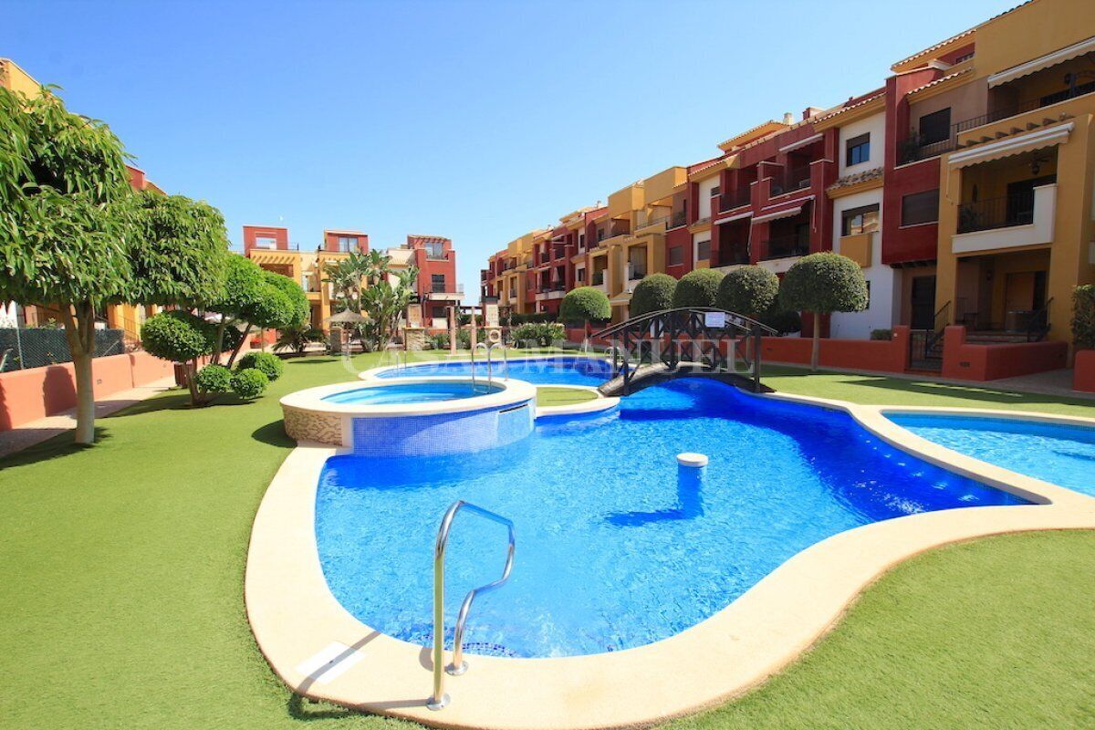 A swimming pool area with multiple pools, surrounded by well-maintained grass and trees.