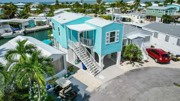 A coastal property with a turquoise house, a dock, and a red car. - 44ft Seawall at Sportsman's Paradise (Summerland Key)