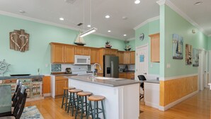 A spacious kitchen with wooden cabinets, a large island with bar stools, and a view of the dining area.
