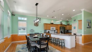 A spacious kitchen with wooden cabinets, a central island, and a dining area with chairs.