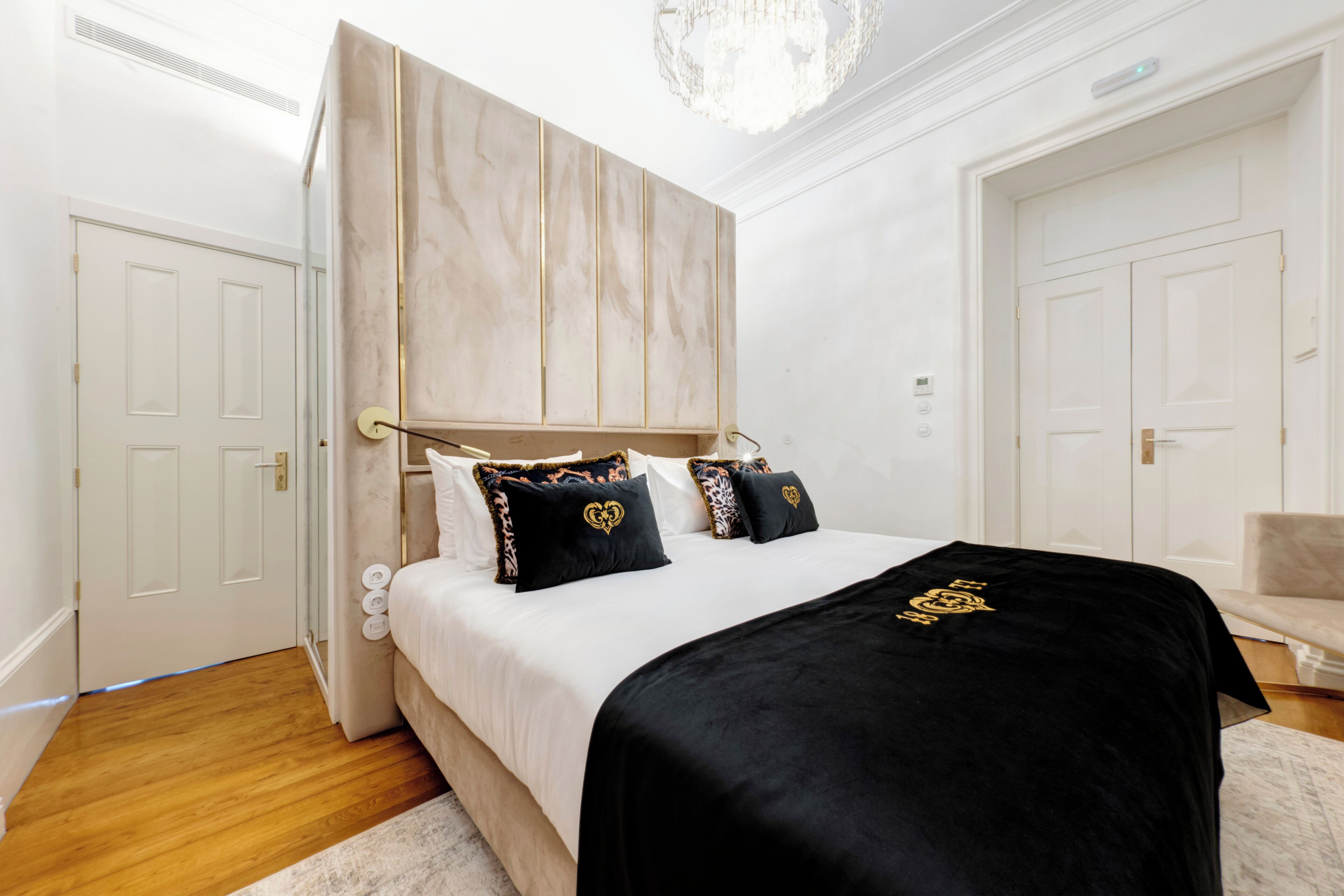 A bedroom with a bed, a headboard, a chandelier, and a door.
