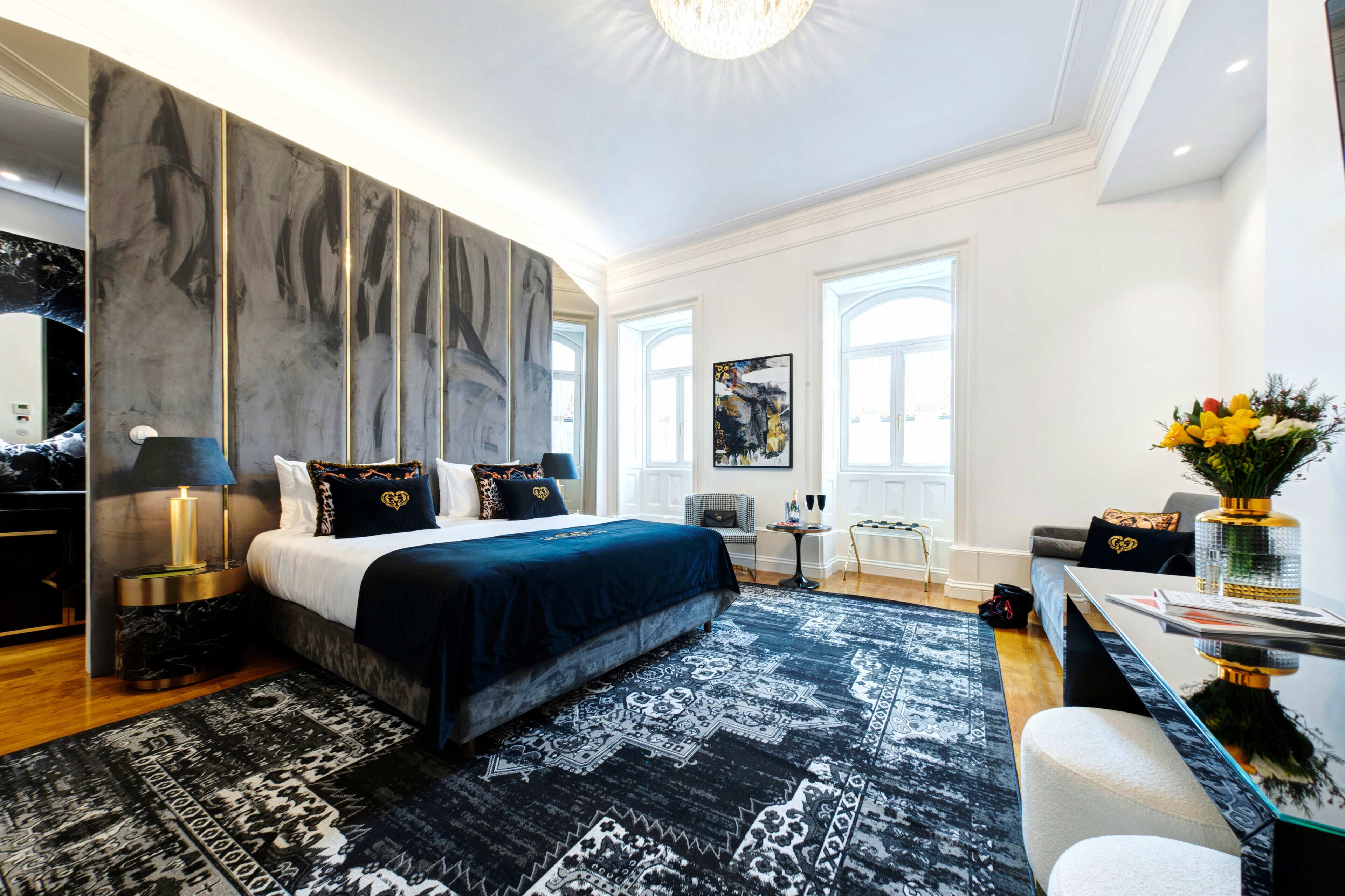A modern bedroom with a large bed, a nightstand, a desk, and a chair.