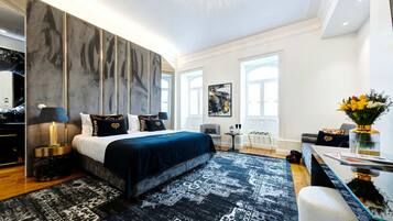 A modern bedroom with a large bed, a nightstand, a desk, and a chair.