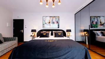Een moderne hotelkamer met een groot bed, twee nachtkastjes met lampen, een gestreept fauteuil en abstracte kunst aan de wanden.