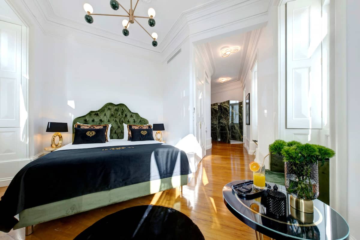 Un dormitorio bien iluminado con una cama grande, una mesita de vidrio y una planta en maceta.