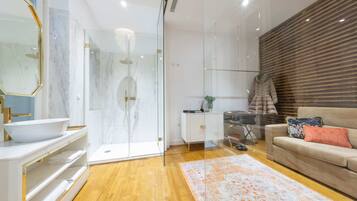 A modern bathroom with a glass shower, marble flooring, and a white vanity with a bowl sink.