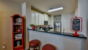 Een keuken met een bar, een rode boekenkast en een welkomstbord.