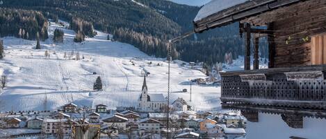 A snow-covered village with traditional wooden houses, a church, and a mountain backdrop.