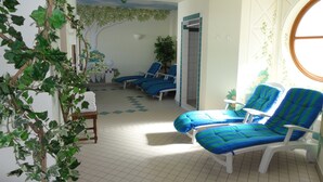 Una habitación con dos sillas azules acolchadas, una mesita y una planta en maceta.