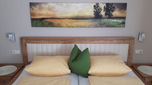 Un dormitorio con cabecera de madera, dos almohadas color beige y una almohada verde.