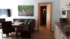 A modern living space with a dining area, a kitchen, and a hallway leading to a bedroom.