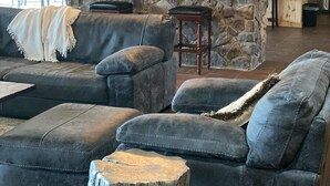 A spacious living room with a stone accent wall, a large gray sectional sofa, and a wooden coffee table. - Your private fishing oasis in Big Sandy  (Big Sandy)
