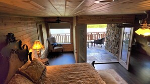 A cozy room with a bed, a chair, a lamp, and a view of an outdoor patio. - Your private fishing oasis in Big Sandy  (Big Sandy)