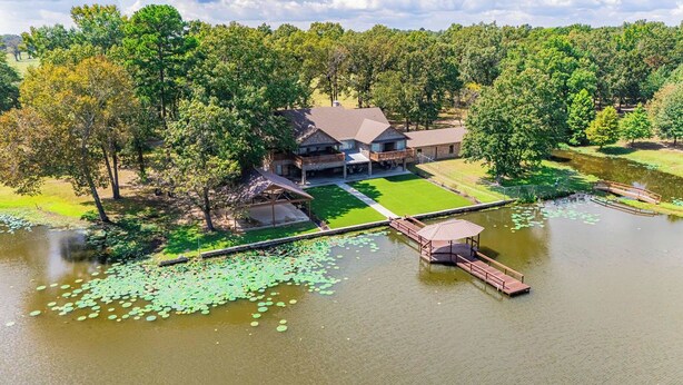 A lakeside property with a house, dock, and a grassy lawn. - Your private fishing oasis in Big Sandy  (Big Sandy)