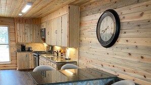 A kitchen with wooden cabinets, a stone island, and bar stools. - Your private fishing oasis in Big Sandy  (Big Sandy)