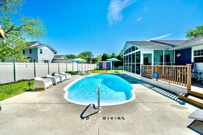 Ein Swimmingpool mit Sprungbrett, umgeben von einer Holzterrasse und Liegestühlen.