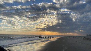 Una playa con un atardecer, olas y un muelle.