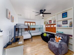 Ein Schlafsaalzimmer mit Etagenbetten, einem Schreibtisch, einem Stuhl und einem Bücherregal.