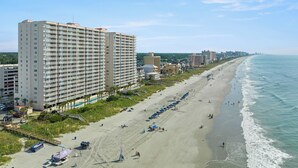 A coastal hotel with multiple floors, a beachside location, and a view of the ocean.